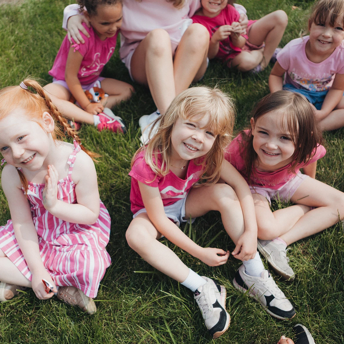 Group of girls sitting on grass smiling Group of girls sitting on grass smiling